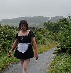 Femme de ménage travestie dans une voie publique sous la pluie